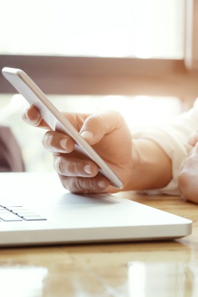 Businessman using laptop and mobile phone for online communication.