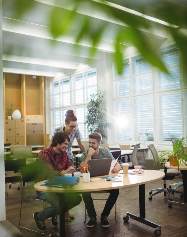 Group of business executives discussing over laptop at their desk in the office